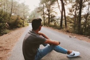 back view photo of man sitting on gray concrete road